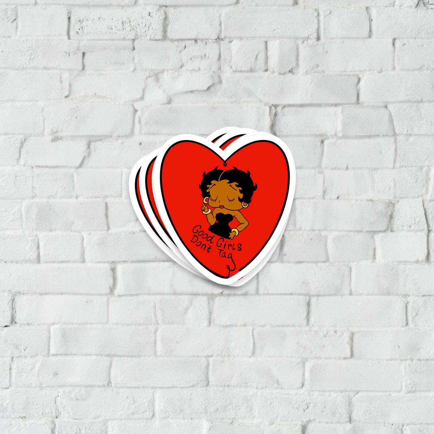 Red heart-shaped sticker with a Betty-Boop design on a white brick wall background.