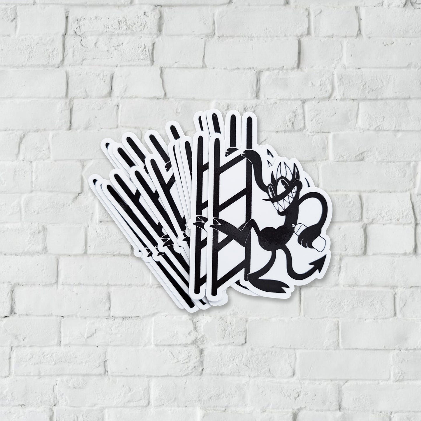 black and white sticker with a devil character climbing a ladder with a white brick background