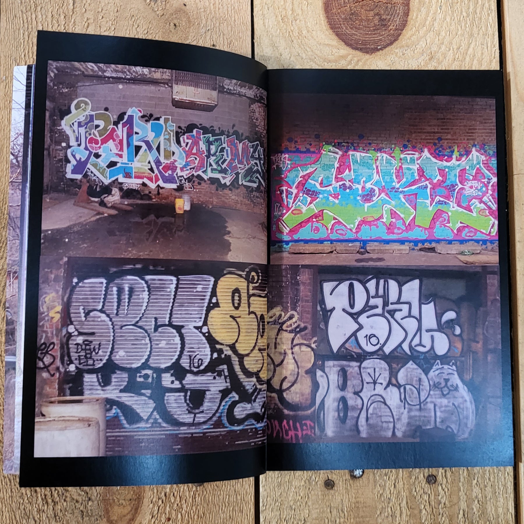 An open magazine, the left and right pages show two photos of graffiti, one on top of the other.