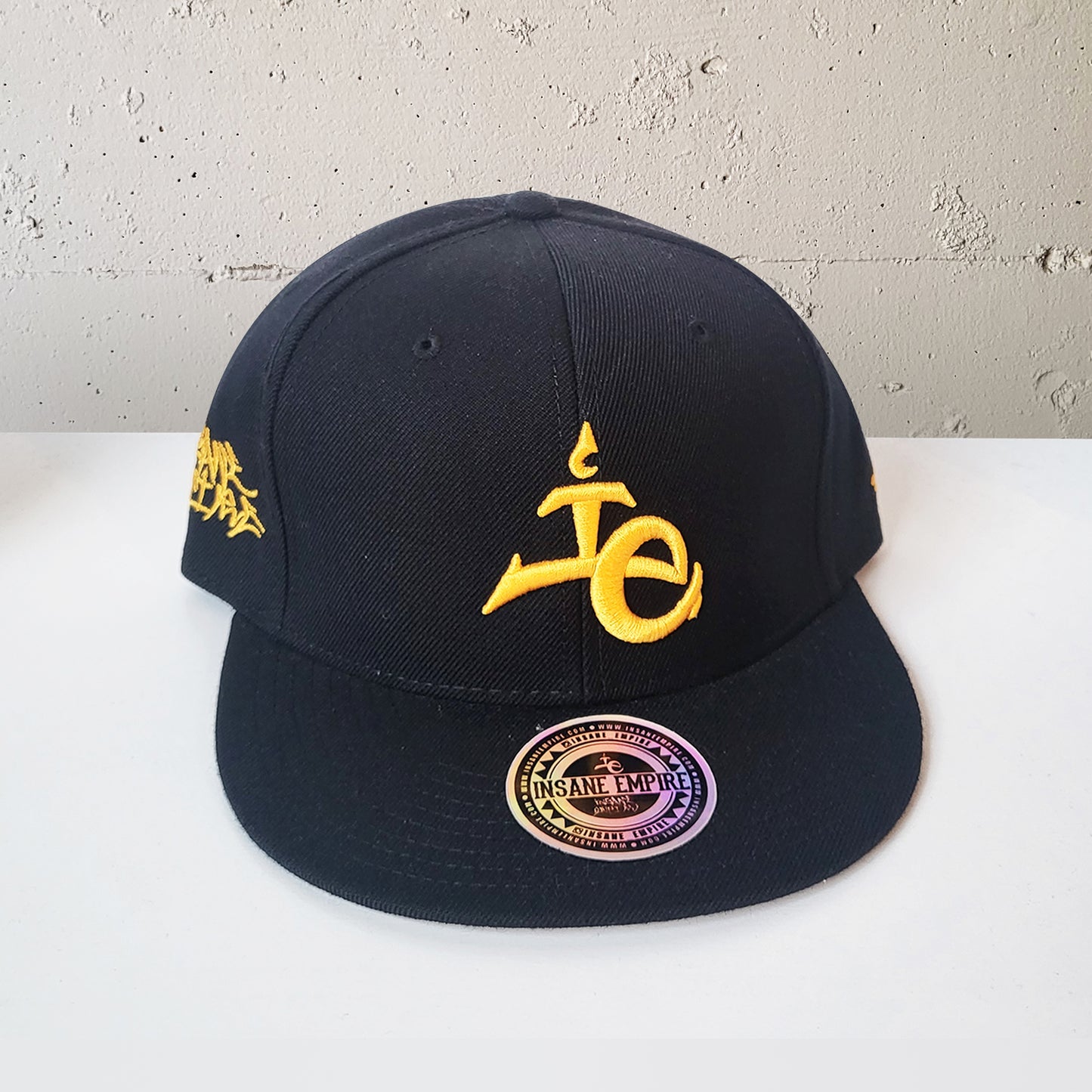 Local artist clothing brand inland empire gold and black snap back lowercase