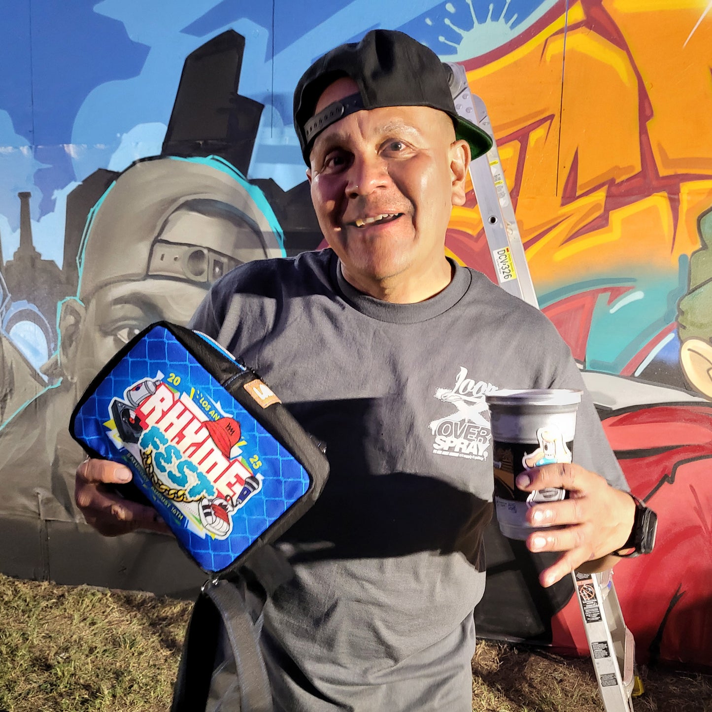 Man wearing a grey 'Overspray X Loop' Shirt with a colorful graffiti mural