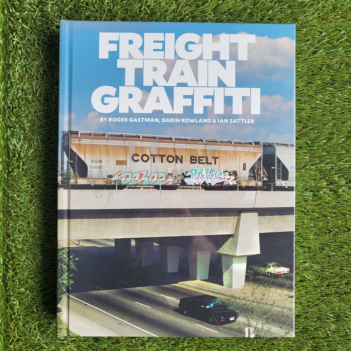 Hardcover book reading 'Freight Train Graffiti' with a photo of a cargo train on a railroad overpass over a freeway with a grass background