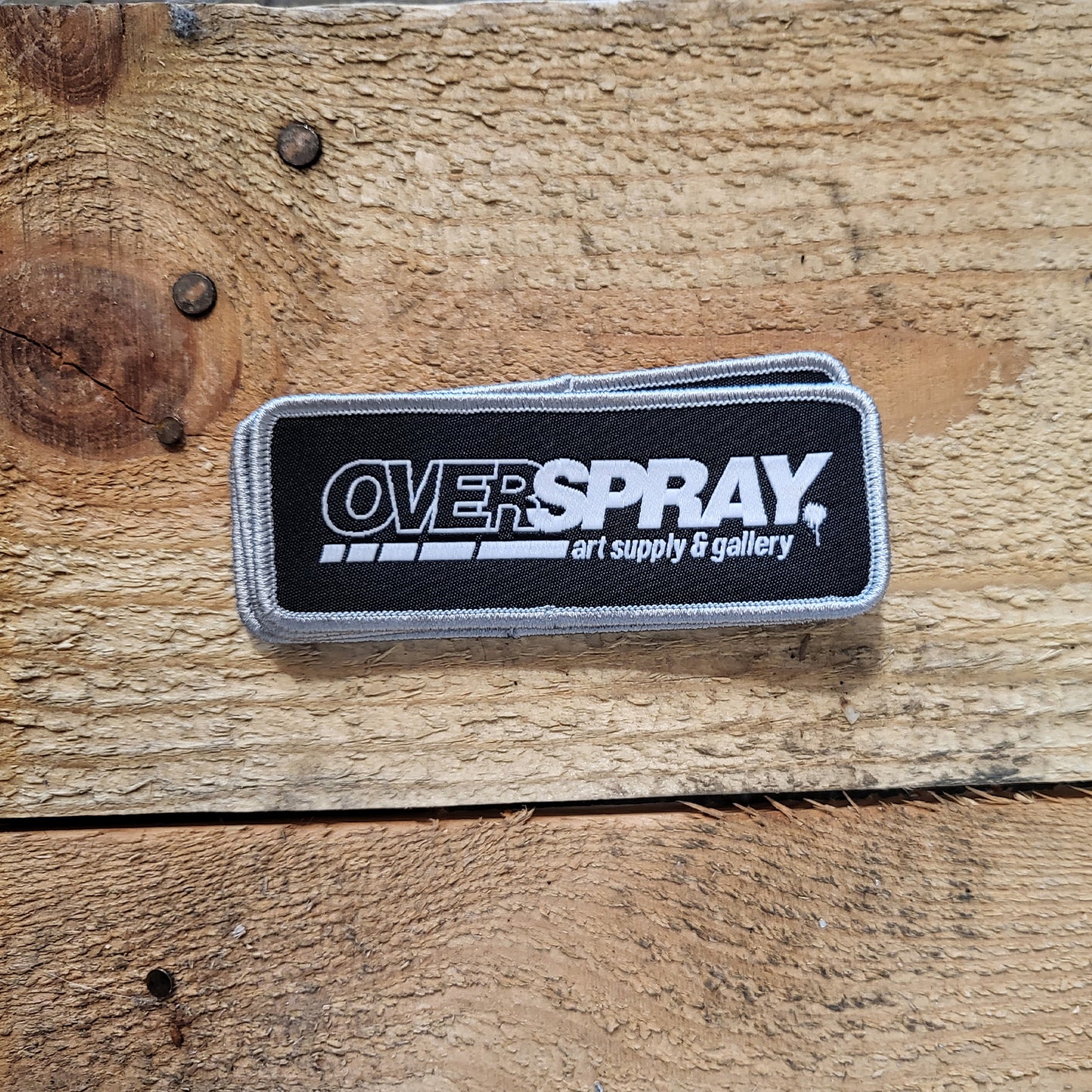 overspray logo patch in black and white with a silver frame