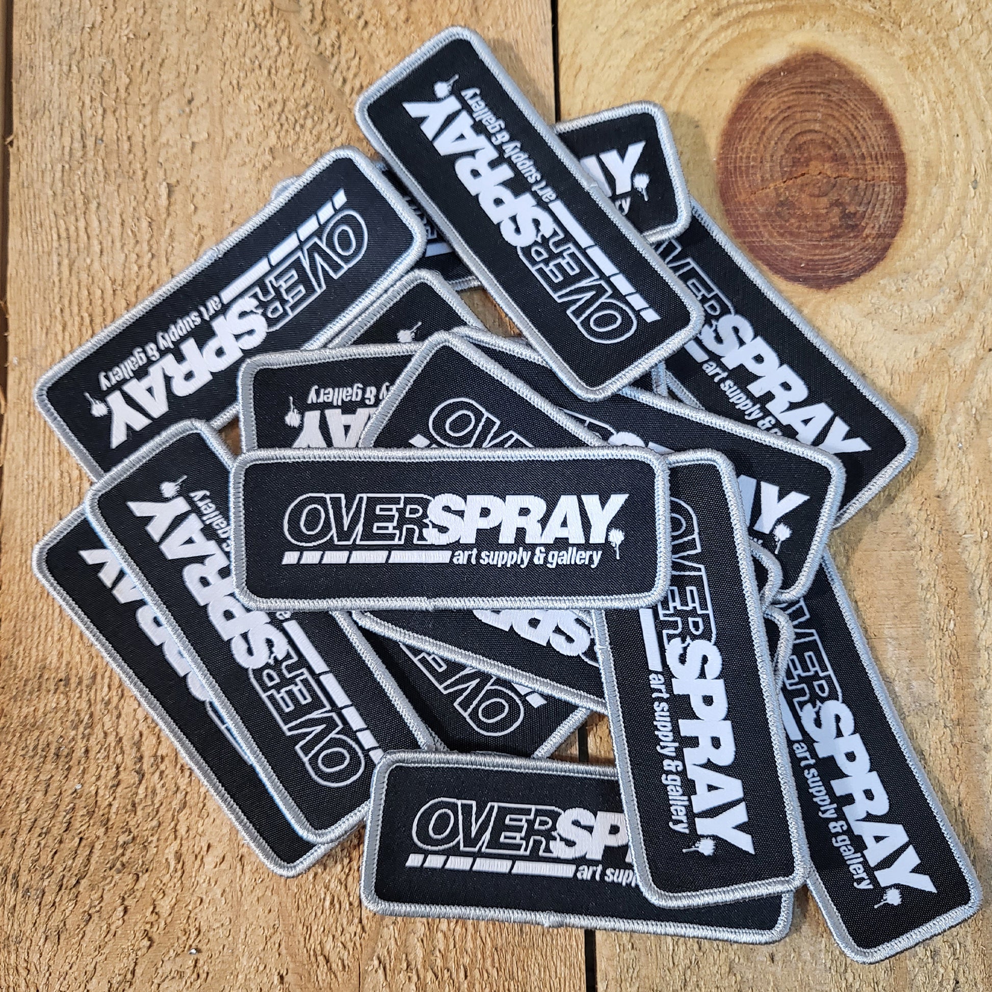overspray logo patch in black and white with a silver frame