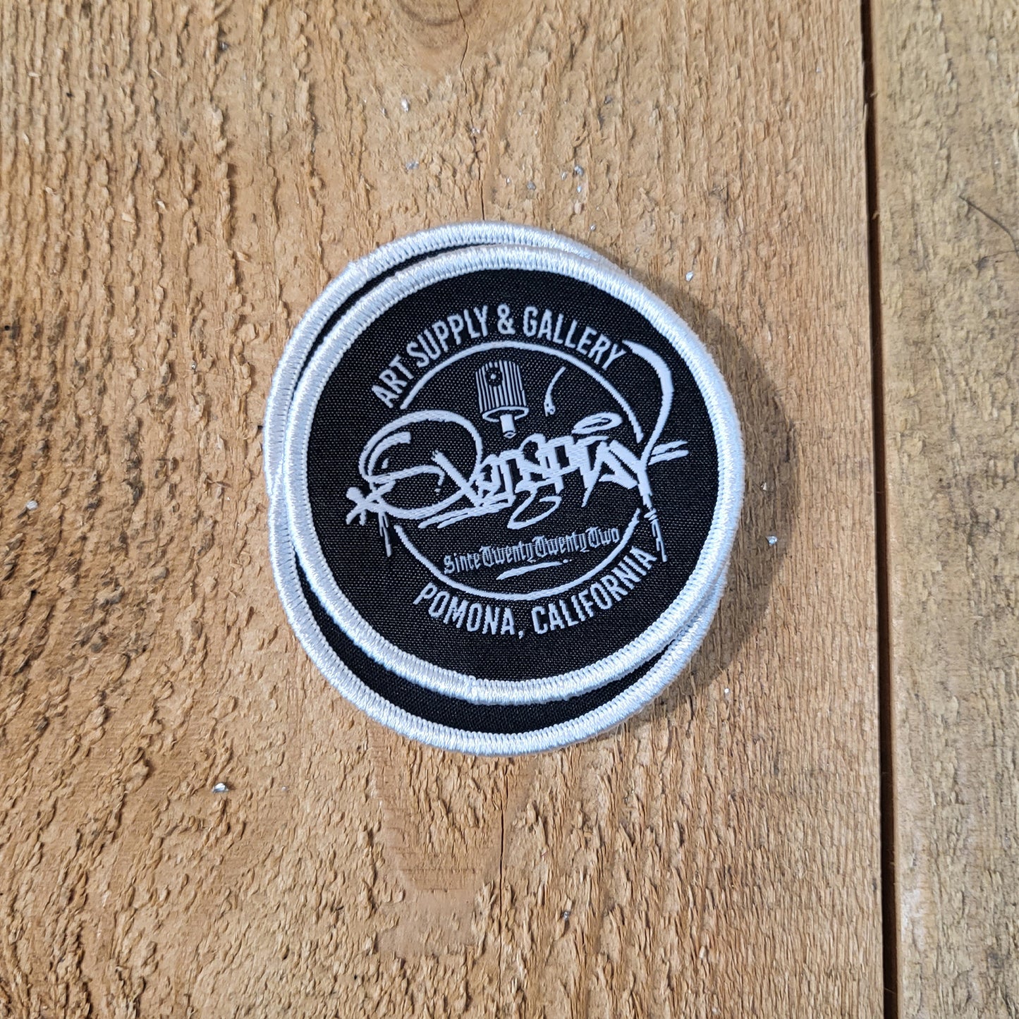round black overspray tag patch with a silver edge
