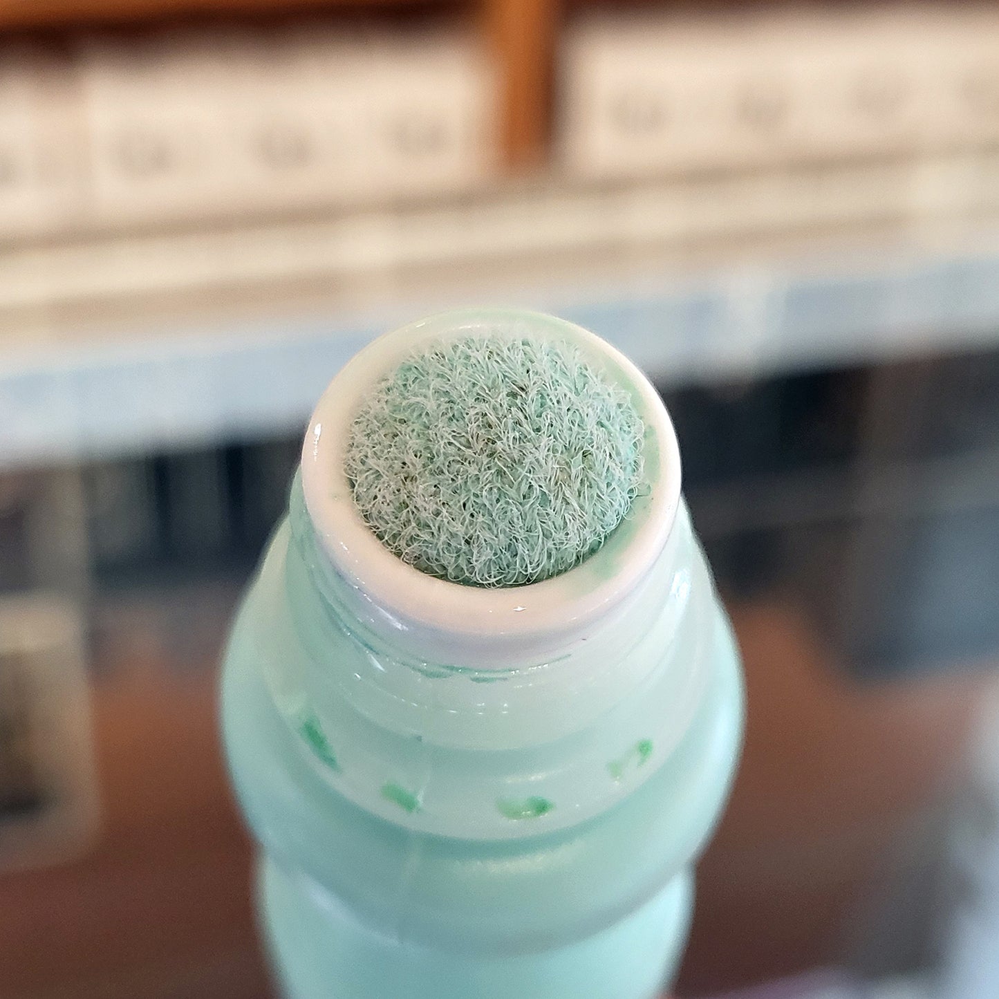 A close up photo of a textured felt marker nib, marker color is aqua with a blurred background.