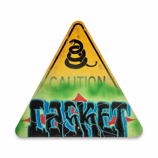 Triangular warning sign with snake symbol and spray-painted text of CASKET on a white background.
