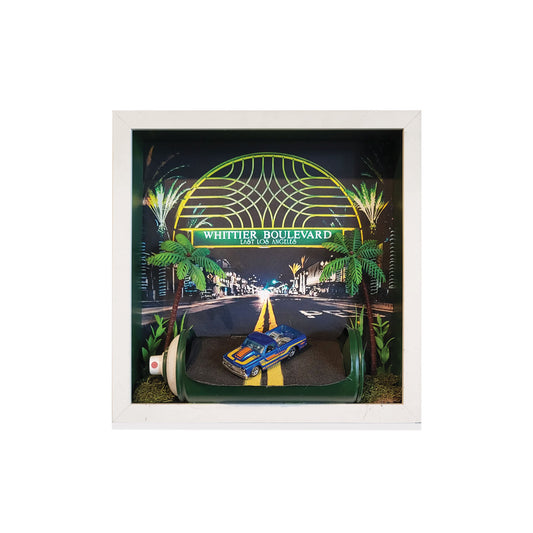 Framed artwork of a car on a road with 'Whittier Boulevard' sign and palm trees.