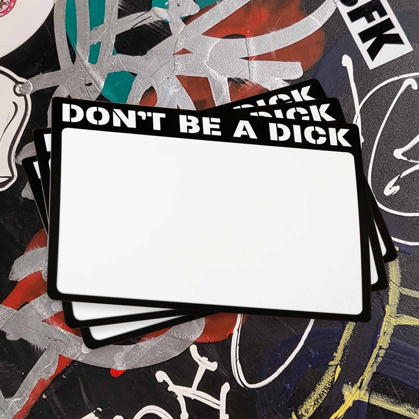 Stack of white stickers with a black boarder reading "Don't Be A Dick".
