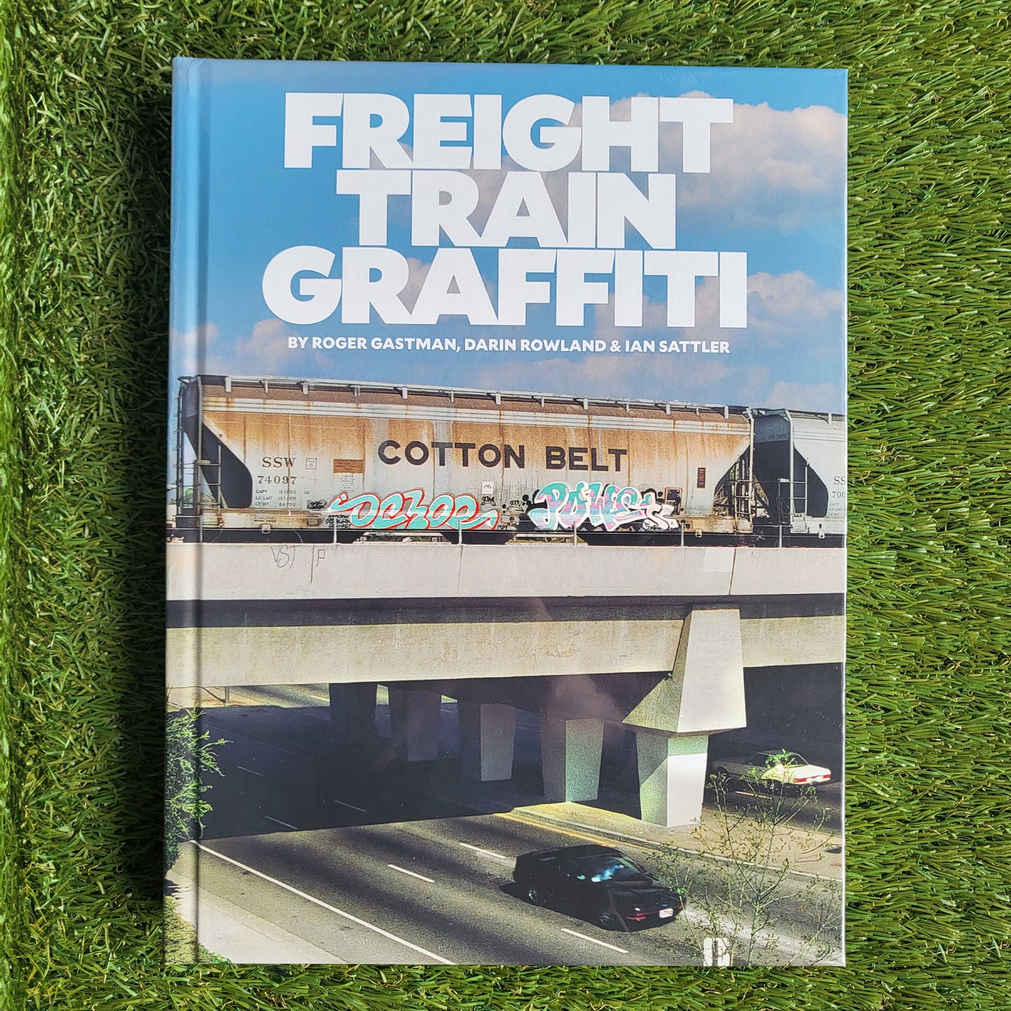 Hardcover book reading 'Freight Train Graffiti' with a photo of a cargo train on a railroad overpass over a freeway with a grass background