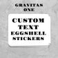 Stack of custom text eggshell stickers on a gray textured background with 'Gravitas One' branding.