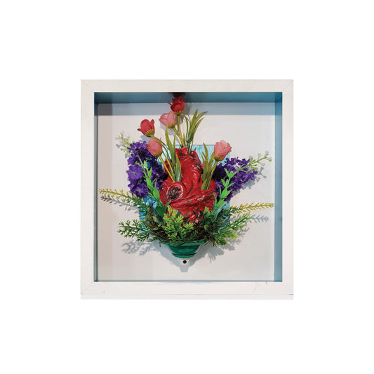 Framed artwork of a heart made of flowers with a white border.