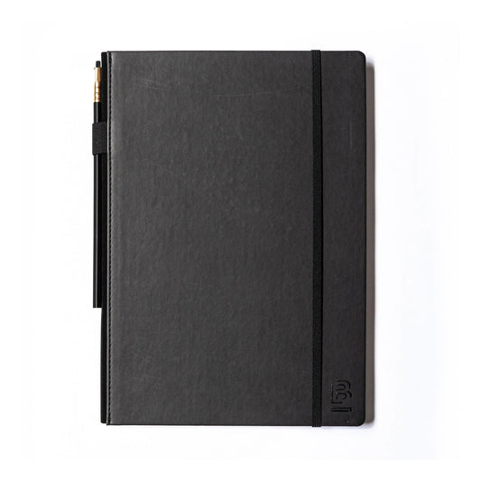 black sketch book with a black graphite pencil and pencil holder lying on a white background