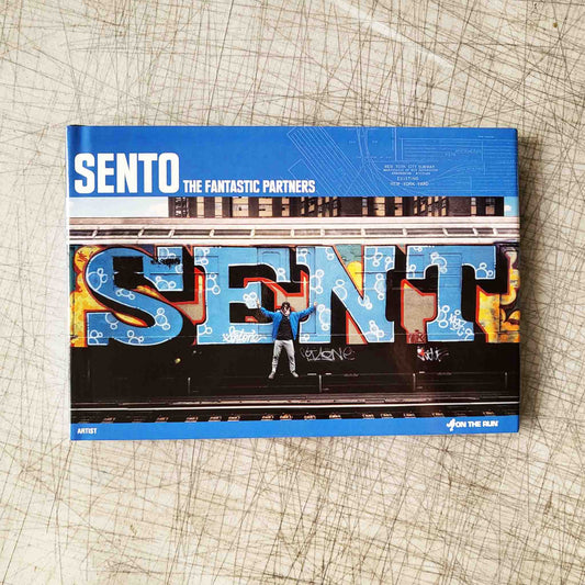 Blue book titled "SENTO - The Fantastic Partners" with a photo of a person standing in front of a graffitied train