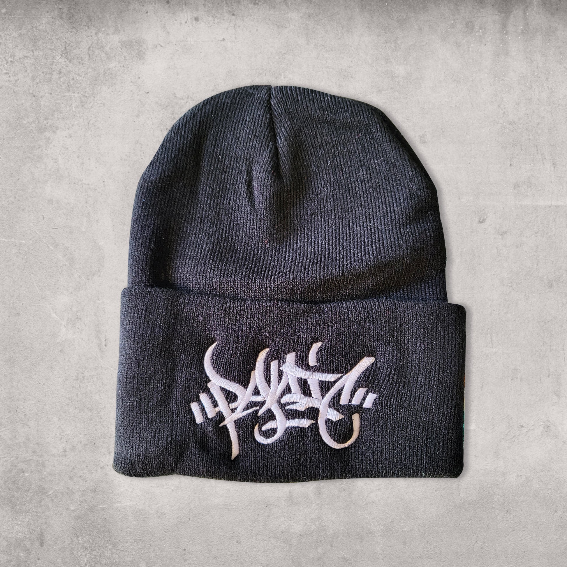 Black beanie hat with white embroidery reading Panic in tag font