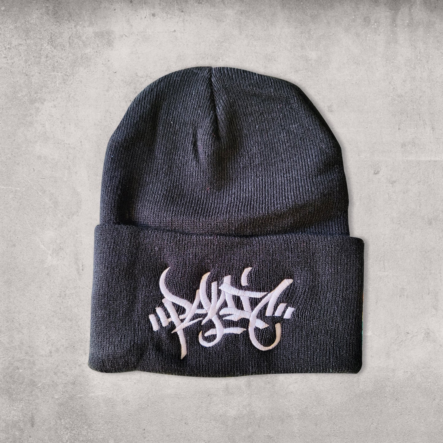 Black beanie hat with white centered  front embroidery reading Panic in tag font