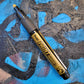 Pentel bullet point paint marker in gold on a colored background