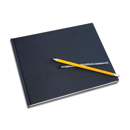 A closed, plain black cover sketchbook with bright white pages.