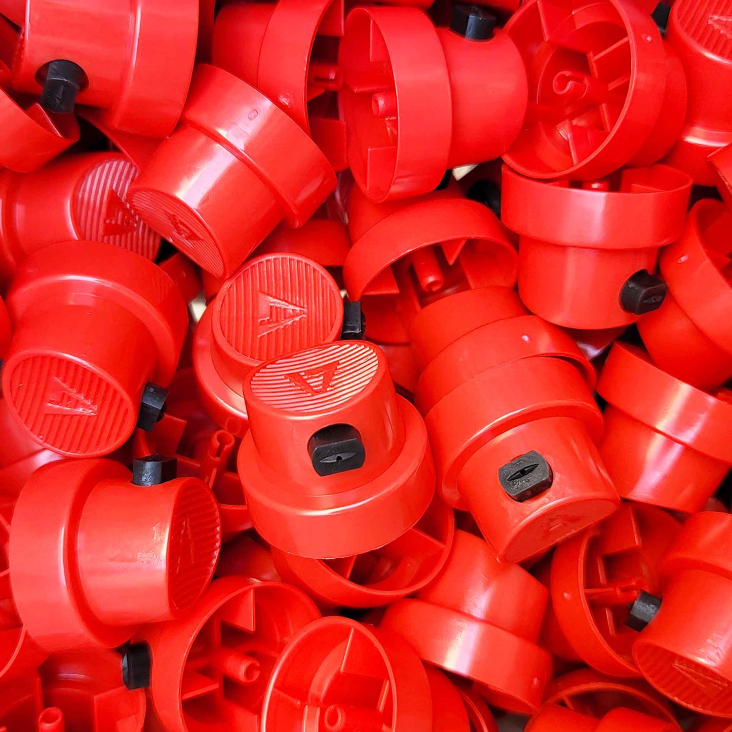 Pile of red aerosol caps with black center inserts.
