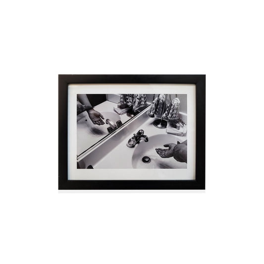 Black framed black and white photo of a bathroom.