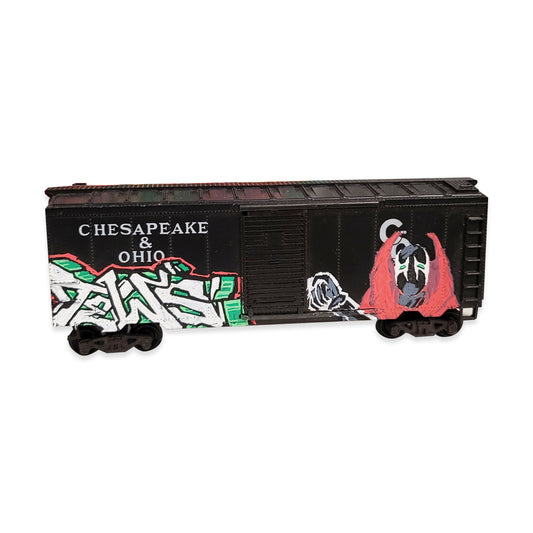 A model black boxcar train car with 'CHESAPEAKE & OHIO' lettering and colorful graffiti-style graphics in green, white, red, and gray, shown on a plain white background.