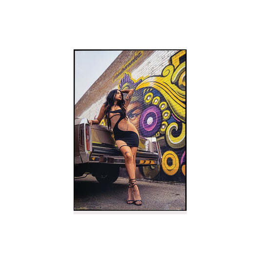 Photo of a woman leaning against a classic car with colorful mural in the background.