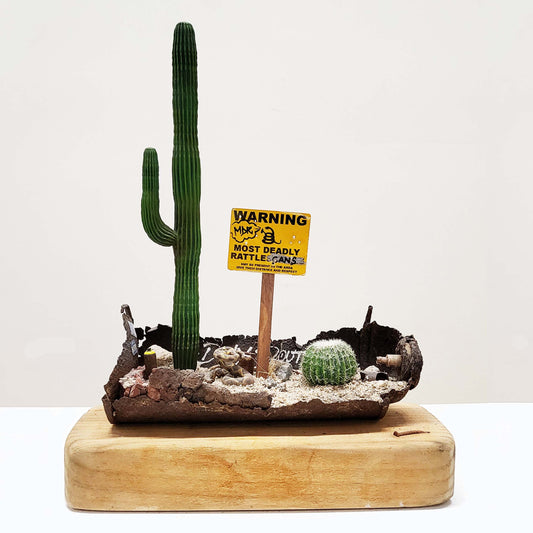 A wooden block with a rusted spray paint can in a miniature desert diorama.