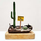 A wooden block with a rusted spray paint can in a miniature desert diorama.