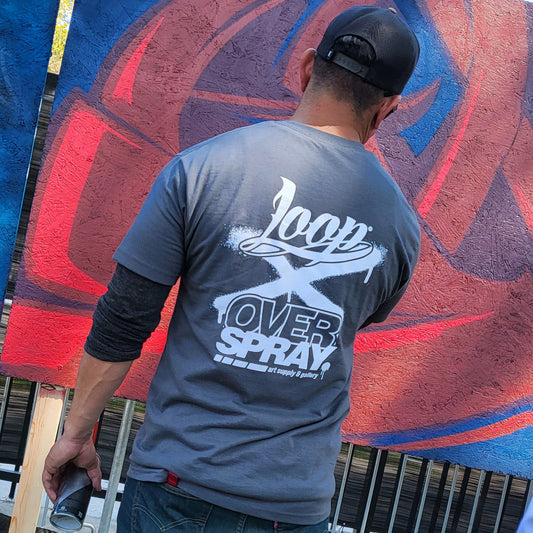 Person wearing a 'Loop Over Spray' t-shirt in front of a colorful mural.