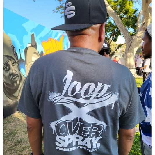 Person wearing a gray 'Loop Over Spray' t-shirt with a mural in the background