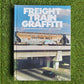 Hardcover book reading 'Freight Train Graffiti' with a photo of a cargo train on a railroad overpass over a freeway with a grass background